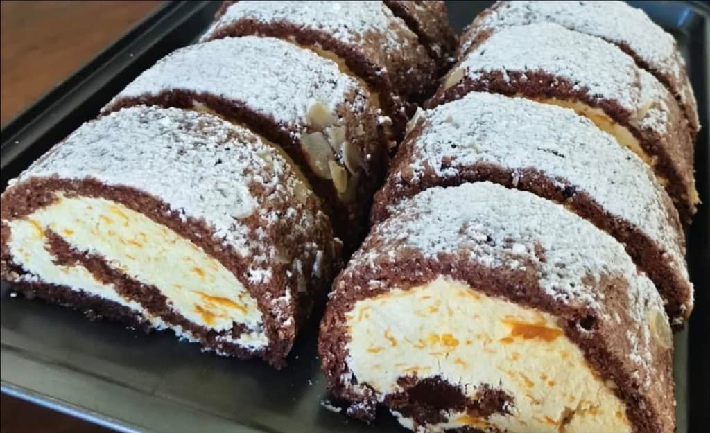 Chocolate Swiss roll slices with orange filling and powdered sugar
